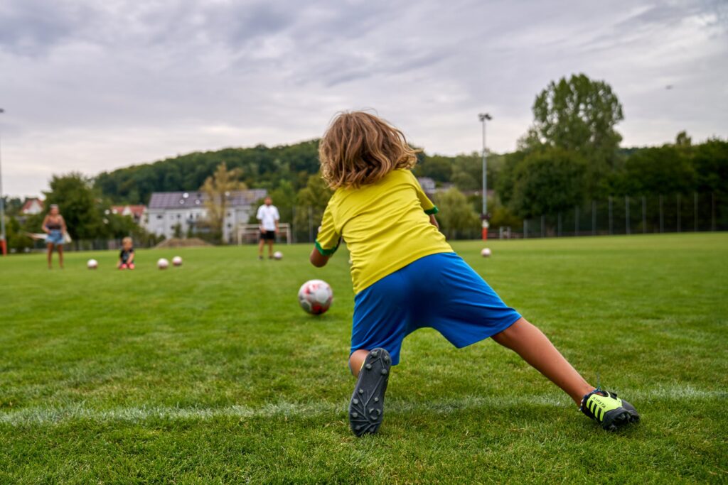 Junger Torhüter auf dem Sportplatz, von hinten